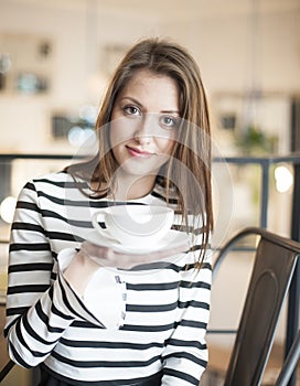 Portrait of young woman holding coffee cup and saucer at cafe