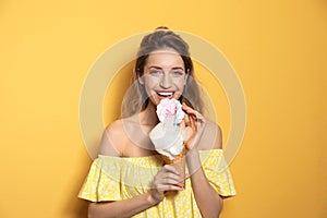 Portrait of young woman holding cotton candy dessert on yellow