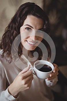Portrait of young woman holding a cup of black coffee