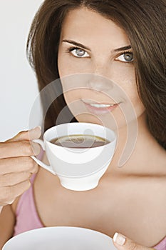 Portrait of young woman holding cup of tea with lemon