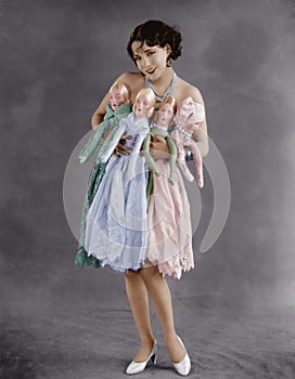 Portrait of young woman holding four dolls