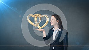 Portrait of young woman holding golden wedding rings on the open hand palm, isolated studio background. Business concept