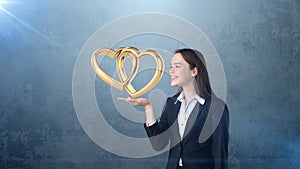 Portrait of young woman holding golden wedding rings on the open hand palm, isolated studio background. Business concept