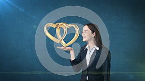 Portrait of young woman holding golden wedding rings on the open hand palm, isolated studio background. Business concept