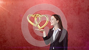 Portrait of young woman holding golden wedding rings on the open hand palm, isolated studio background. Business concept