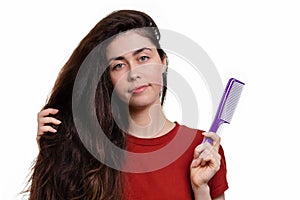 Portrait of a young woman holding her thick dark hair and comb for combing. White background. Hair care concept