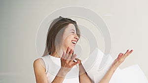 Portrait of young woman holding stack of blueprints and trying to throw it up in the air. Girl throwing papers up and