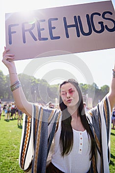 Boho woman holding up free hug sign at festival