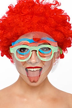 Portrait of a young woman in the image of a clown with a red wig on her head
