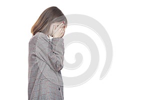 Portrait of a young woman in a jacket holding her hands near her face. Crying, tears, years. Isolated on white