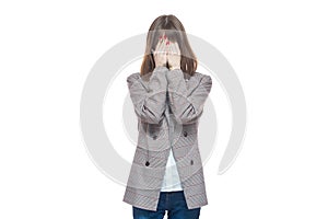 Portrait of a young woman in a jacket holding her hands near her face. Crying, tears, years. Isolated on white