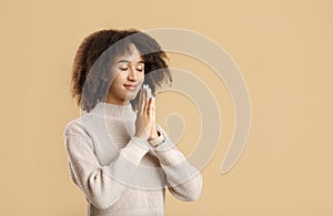 Portrait of young woman keeping palms together and praying, meditating