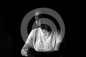 Portrait of young woman kneeling and praying in silent prayer pose, on black and white abstract art background. Believe in God.