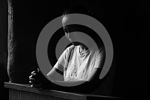 Portrait of young woman kneeling and praying in silent prayer pose, on black and white background. Ash Wednesday concept. photo