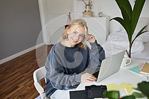 Portrait of young woman, lifestyle blogger, recording vlog video about her life and daily routine, sitting in front of