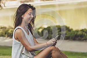 Portrait of young woman listening to the music on the phone in the park