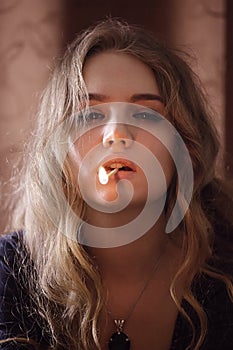 Portrait of young woman with lit match in mouth