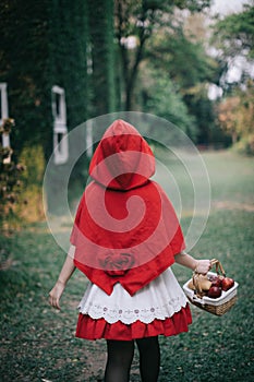 Portrait young woman with Little Red Riding Hood costume in green tree park