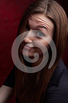 Portrait of a young woman with long brown hair, on a red textured background