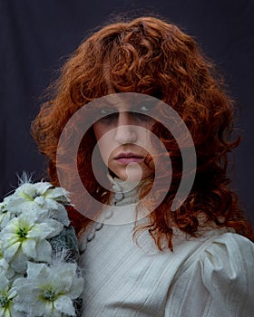 Portrait of a young woman with long curly red hair.