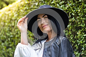 Portrait of a young woman looking at the camera and holding her hat