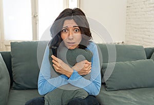 Portrait of a young woman looking scared and shocked watching scary movie on TV