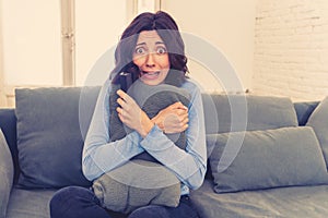 Portrait of a young woman looking scared and shocked watching scary movie on TV