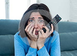 Portrait of a young woman looking scared and shocked watching scary movie on TV