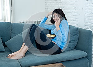 Portrait of a young woman looking scared and shocked watching scary movie on TV