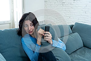 Portrait of a young woman looking scared and shocked watching scary movie on TV