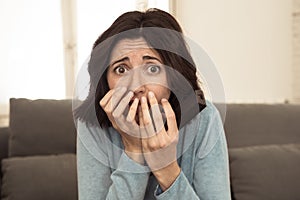 Portrait of a young woman looking scared and shocked watching scary movie on TV