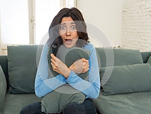 Portrait of a young woman looking scared and shocked watching scary movie on TV