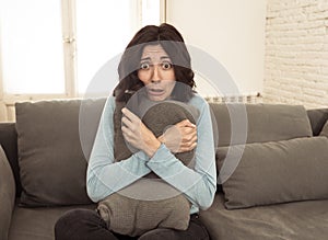 Portrait of a young woman looking scared and shocked watching scary movie on TV