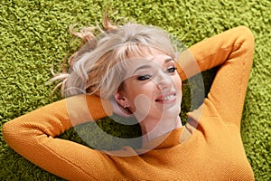 Portrait of young woman lying on green carpet
