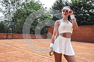 Portrait of young woman model wearing fashionable tennis dress, posing on tennis court