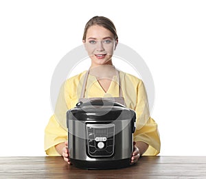 Portrait of young woman with modern multi cooker at table