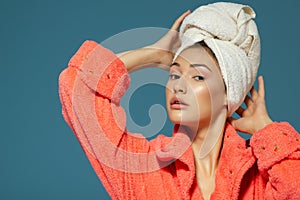 Portrait of young woman during morning procedures. Charming teen girl with towel on her head wearing bathrobe