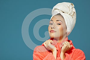 Portrait of young woman during morning procedures. Charming teen girl with towel on her head wearing bathrobe