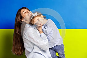 Portrait of young woman, mother with her little girl, daughter isolated over blue and yellow Ukrainian flag background