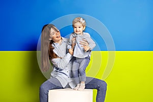 Portrait of young woman, mother with her little girl, daughter isolated over blue and yellow Ukrainian flag background