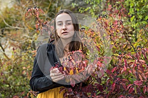 Portrait of young woman near autumn leaves in warm light