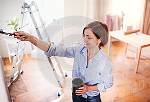 A portrait of young woman painting wall black. A startup of small business.