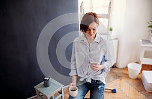 A portrait of young woman painting wall black. A startup of small business.