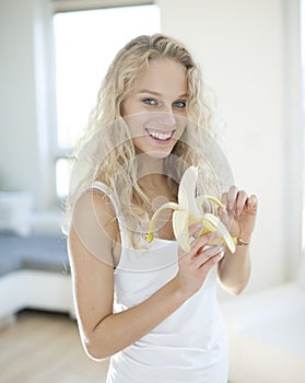 Portrait of young woman peeling banana in house