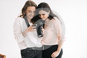 Portrait of young woman photographer and female model together viewing pictures on camera screen.