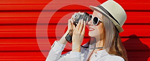 Portrait of young woman photographer with film camera over red background