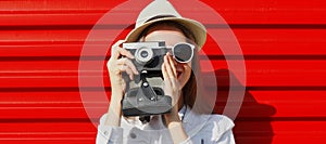 Portrait of young woman photographer with film camera over red background