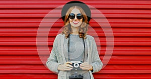 Portrait young woman photographer with vintage film camera on a red background