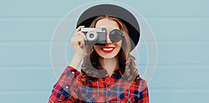 Portrait of young woman photographer with vintage film camera wearing a black round hat