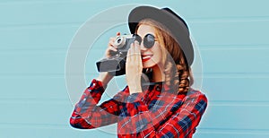 Portrait of young woman photographer with vintage film camera wearing a black round hat